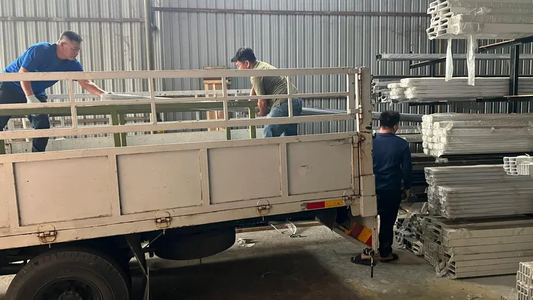 U Tech employees handling aluminum profiles and loading a delivery truck at the warehouse